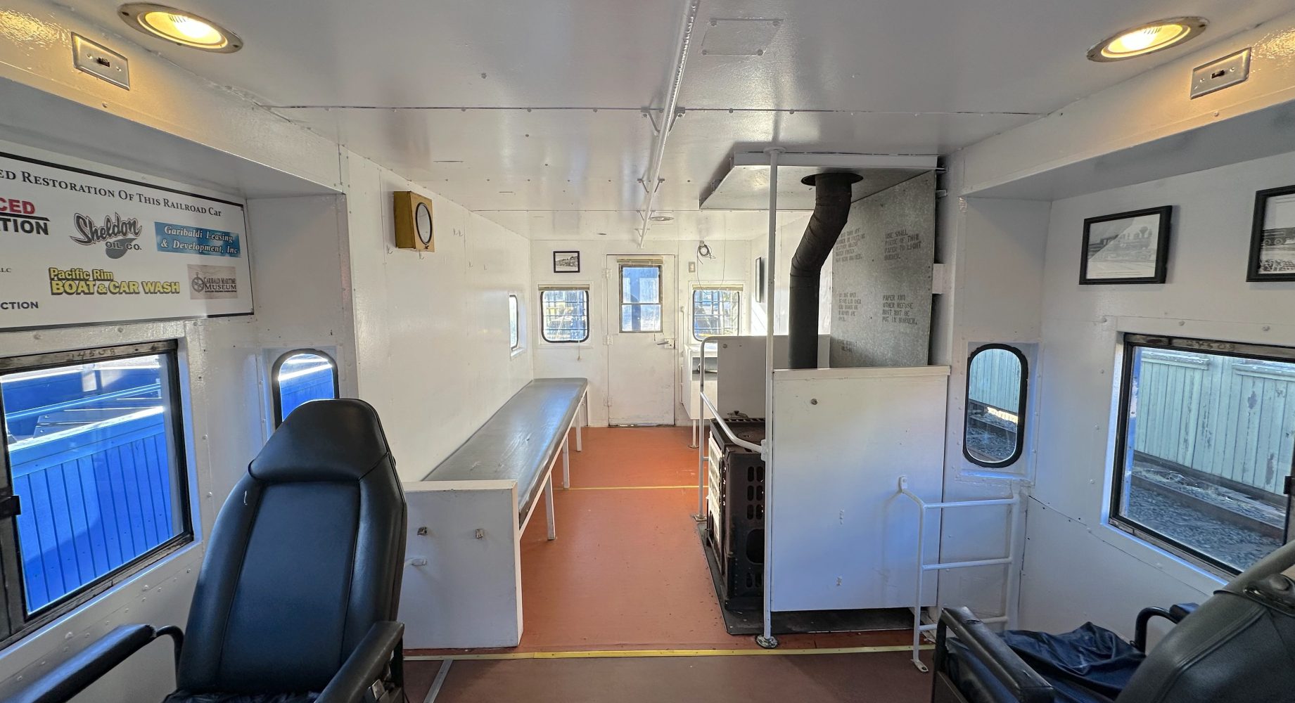 Inside view of a retrofitted train cabin with chairs, table, stove, and signs on walls.
