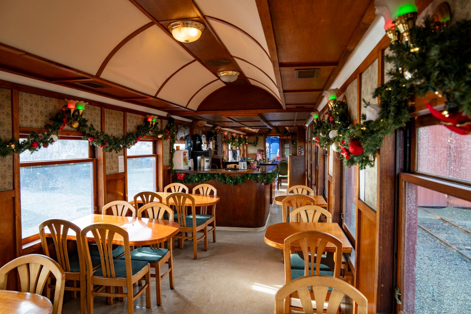 Vintage train dining car decorated with Christmas garlands and wooden furniture.