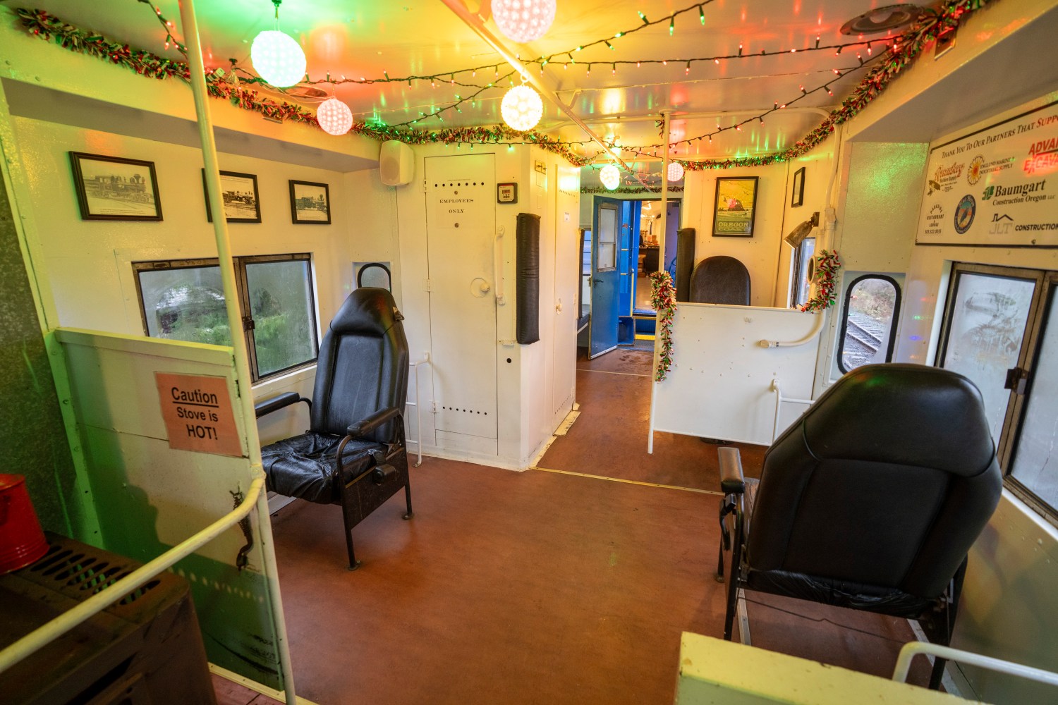 Decorated train carriage interior with chairs and festive lights.