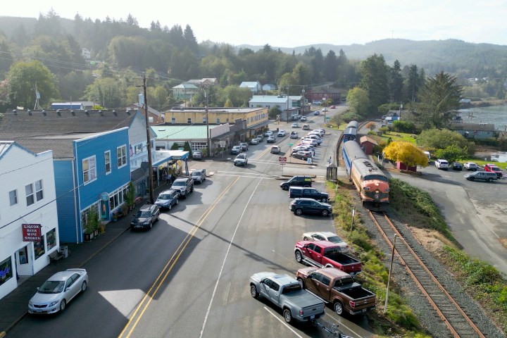 Aerial view of a small town with cars parked along streets and a train on nearby tracks.