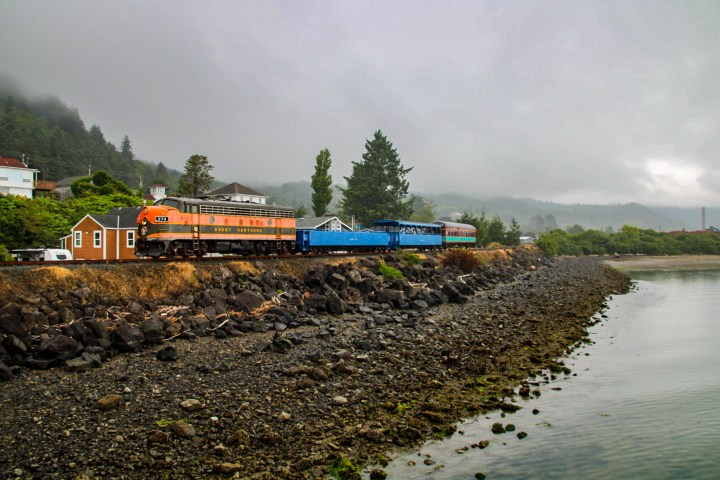 a large long train on a track with smoke coming out of the water