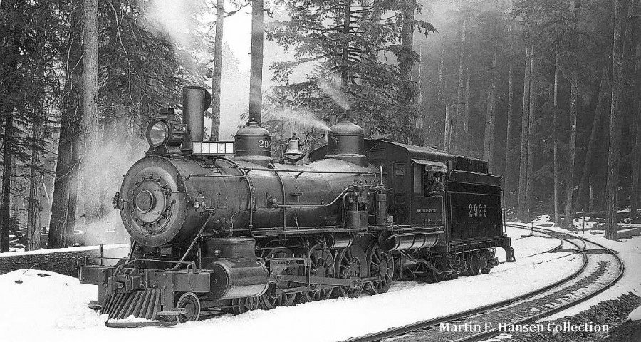 sp-2929-900×480 (1) a train traveling down train tracks near a forest