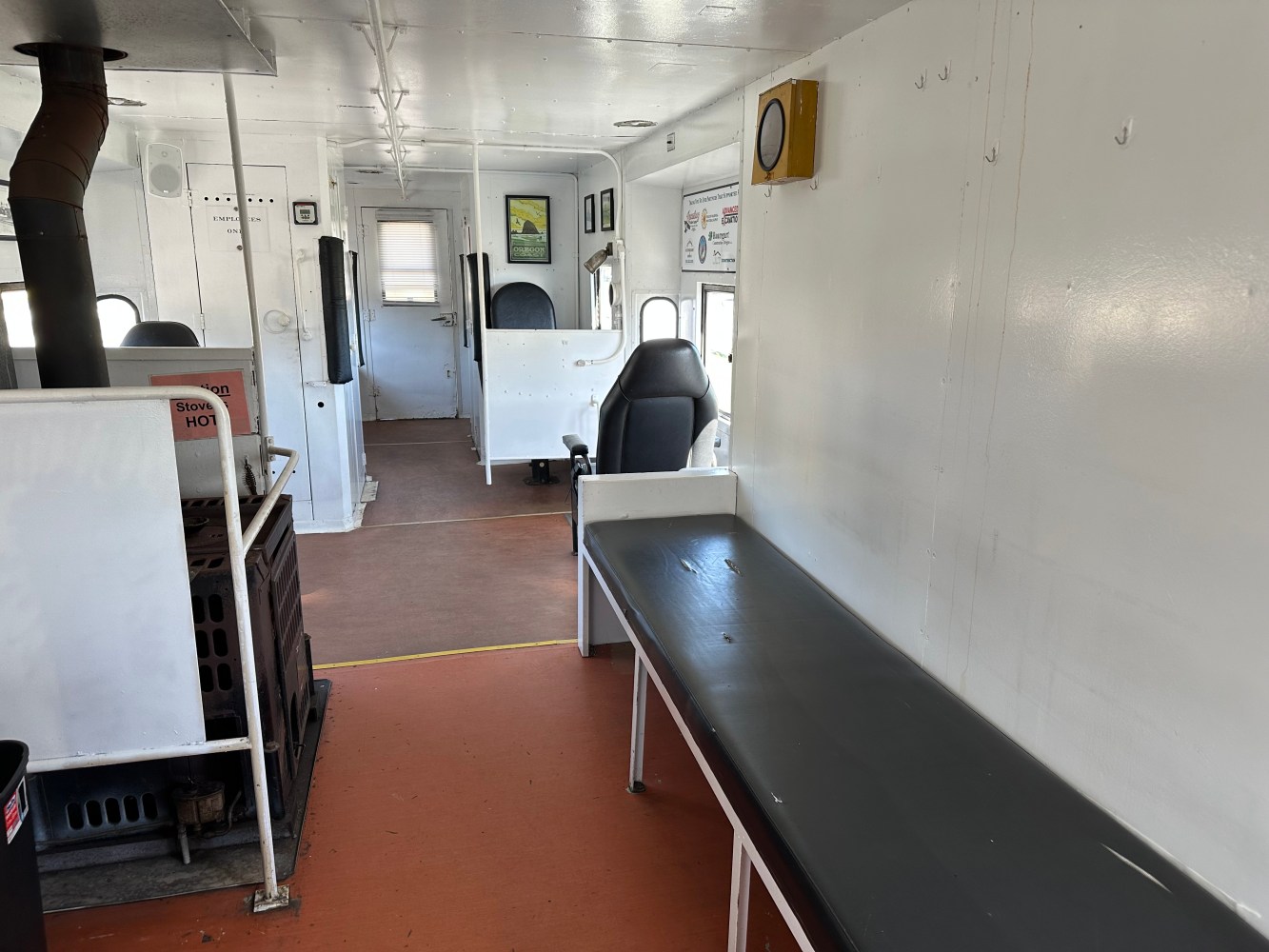 Interior of nostalgic train car with benches, stove, and black chairs.