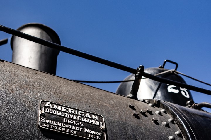 Close-up of historic locomotive with company plaque against a clear blue sky.